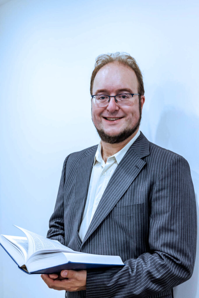 A man in a suit holding a book advises about employer-employee relations.